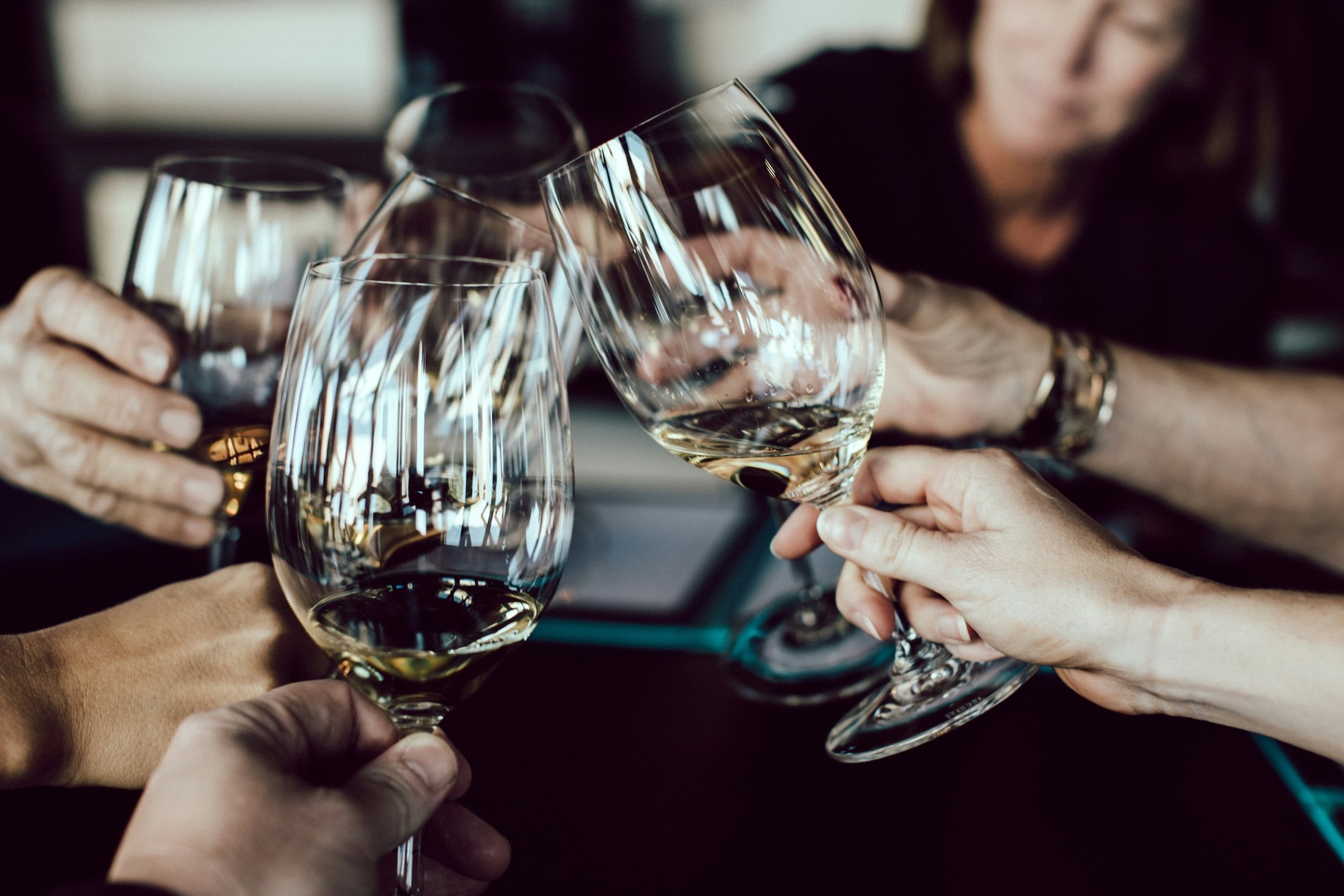 A group of people clinking glasses of white wine.