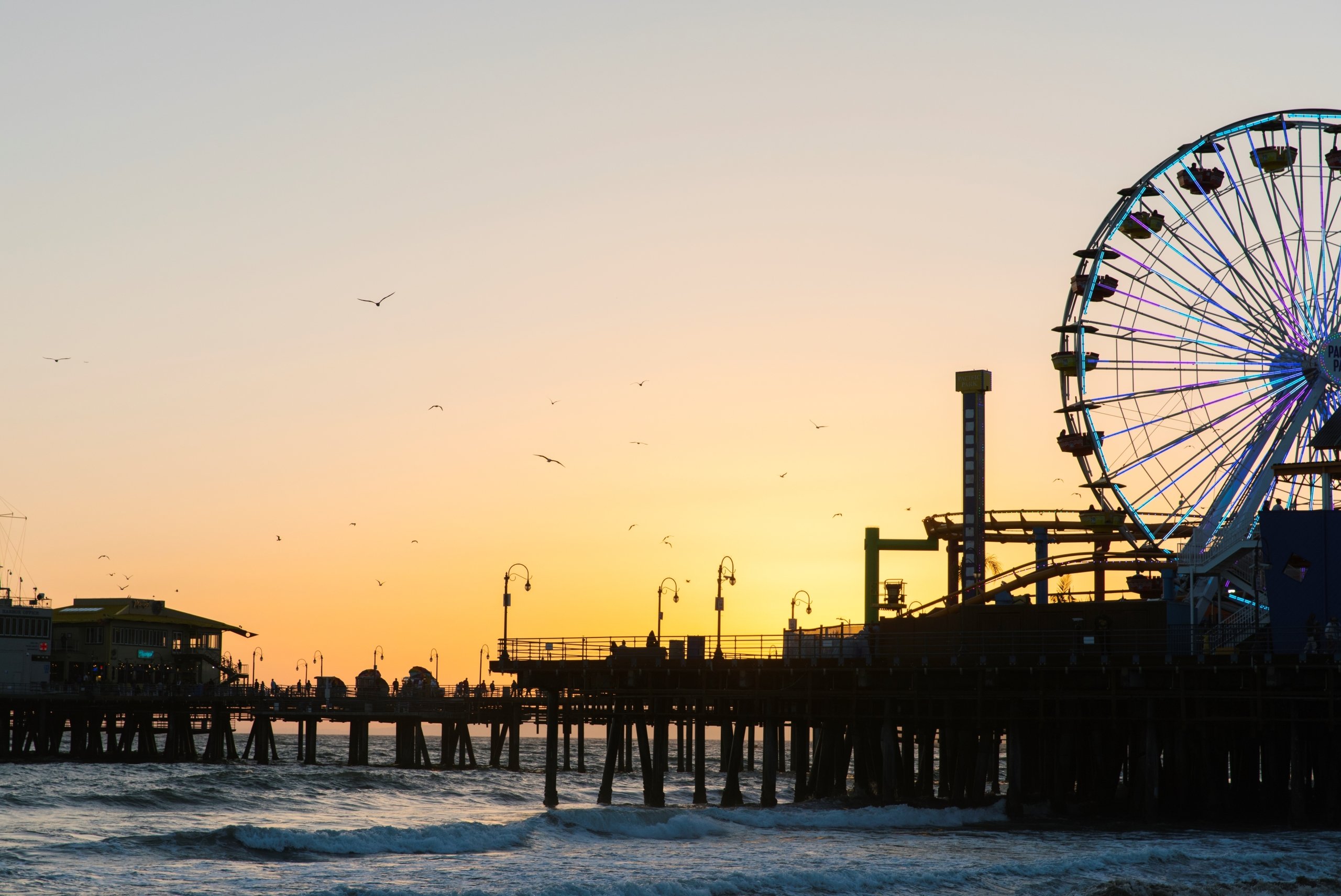 The silhouette of the Santa Monica Pier and ferris wheel at sunset.