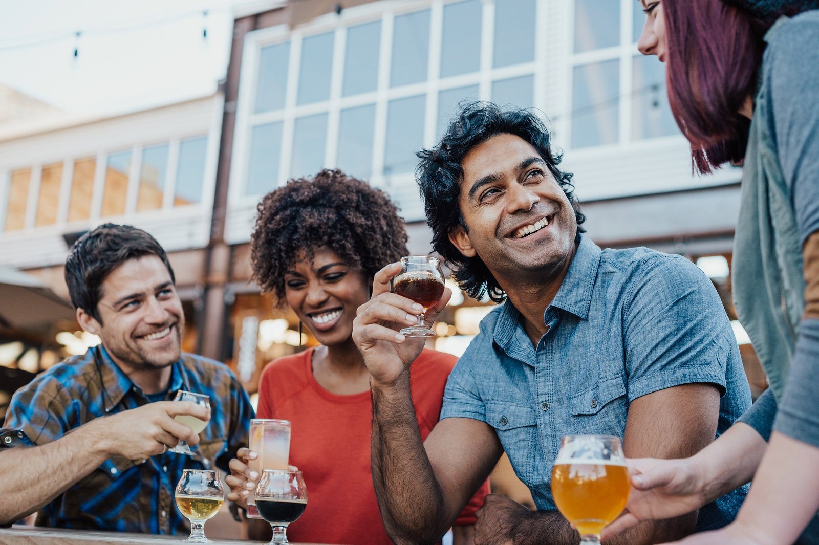 A group of people laughing and enjoying craft beer on a patio.