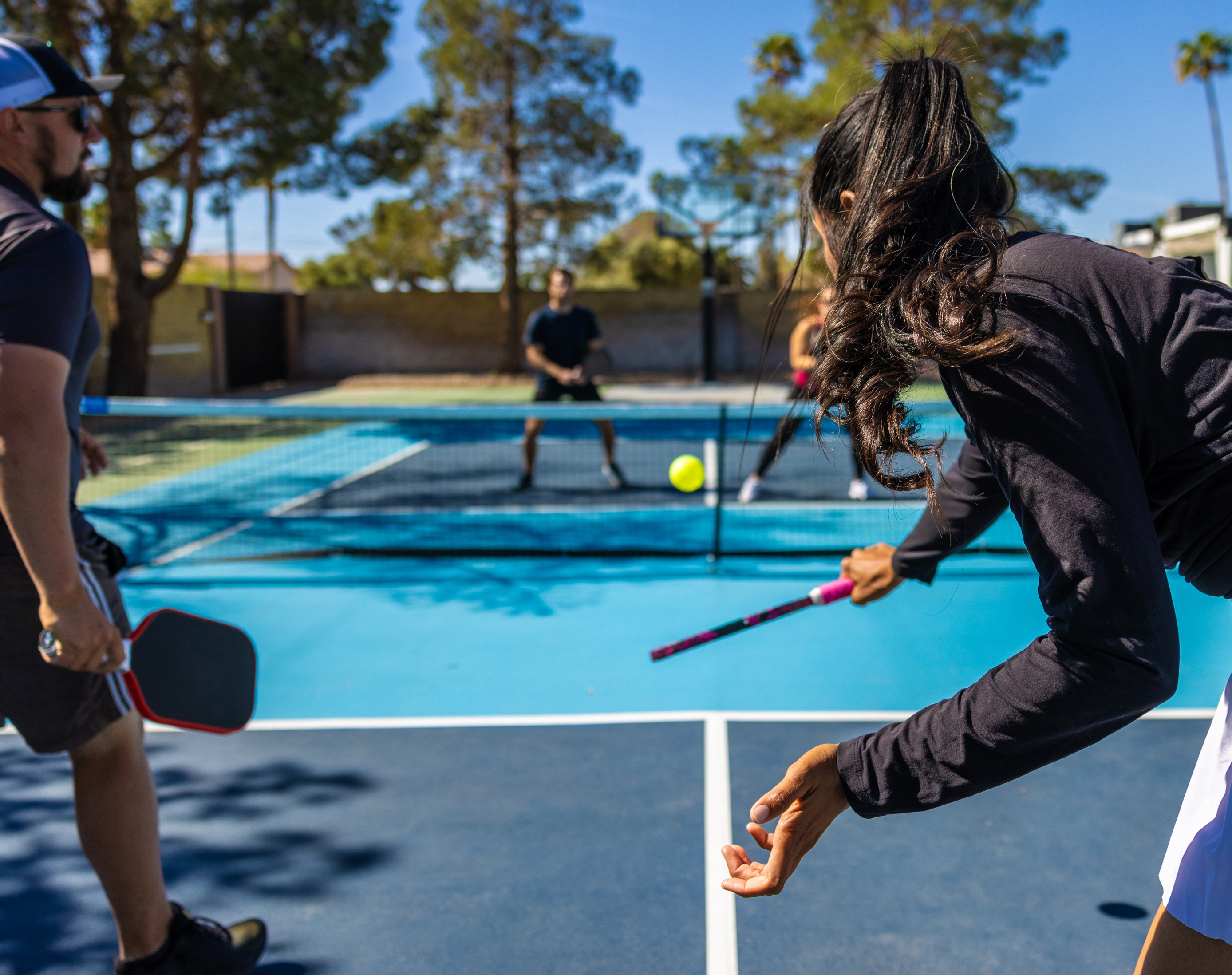 Four people playing pickle ball on the outdoor court at the Fairmont Claremont Club.