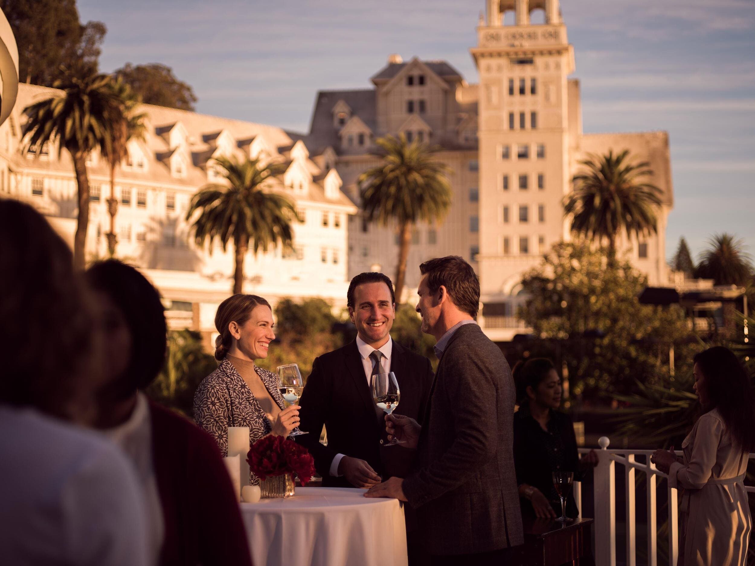 A group of people conversing at an outdoor event, with Fairmont Claremont in the background.