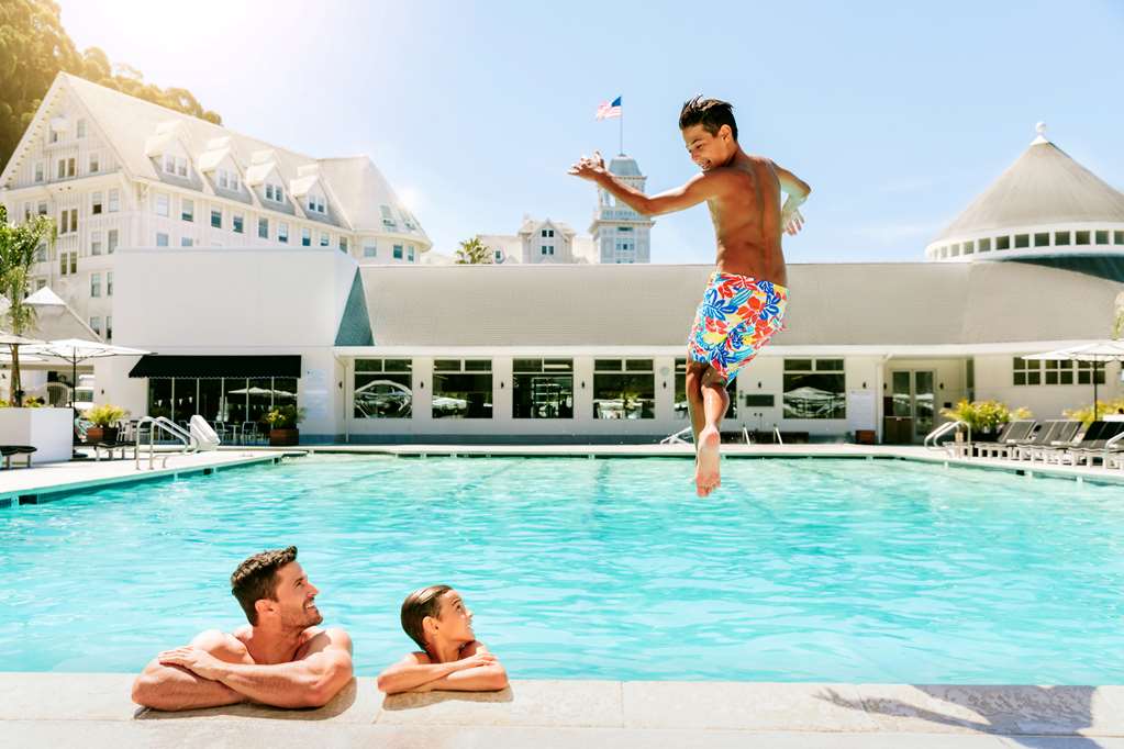 A child jumps into the pool while his father and brother watch.