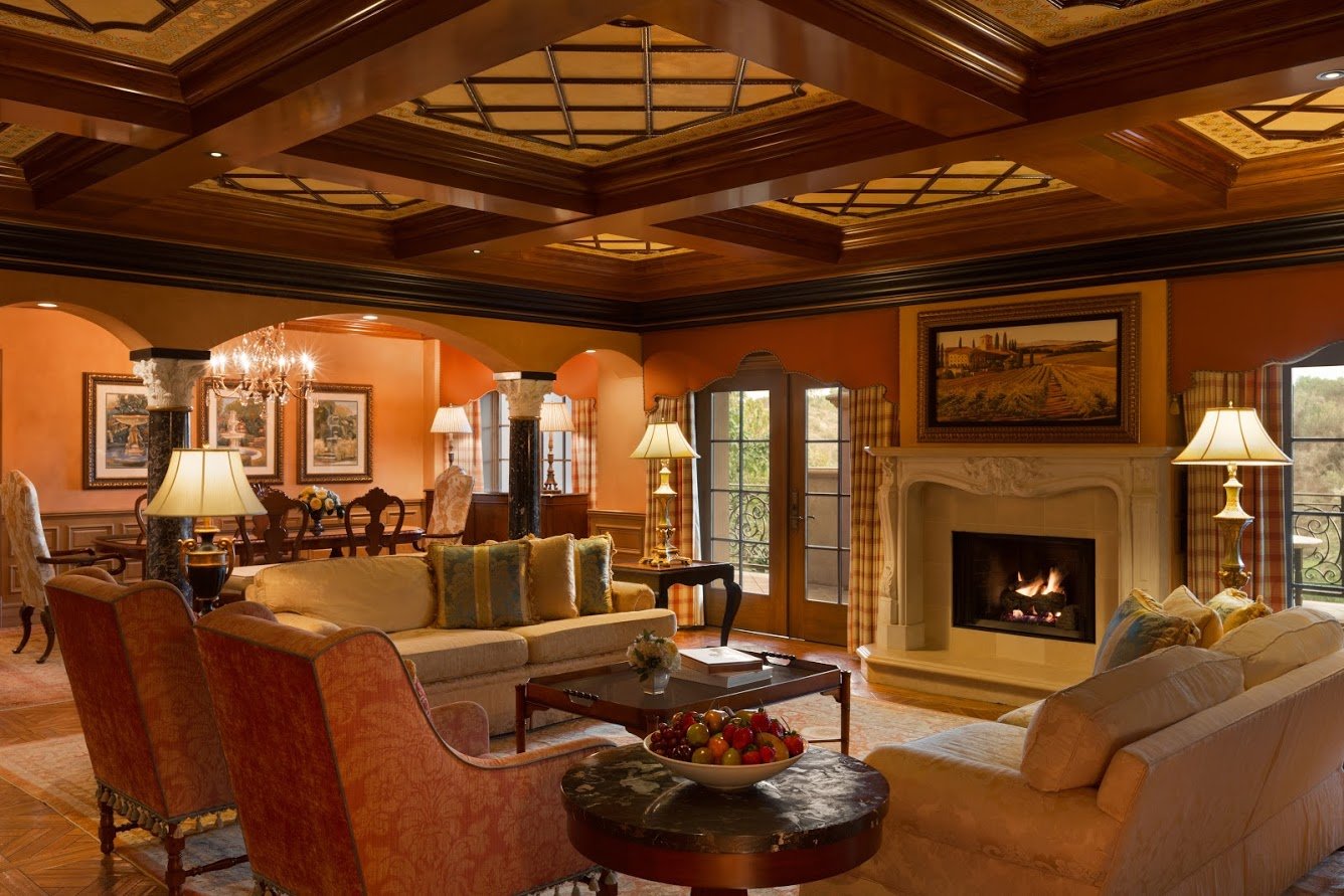 The warm seating and dining area with a lit fireplace in the Grand Suite at Fairmont Grand Del Mar.