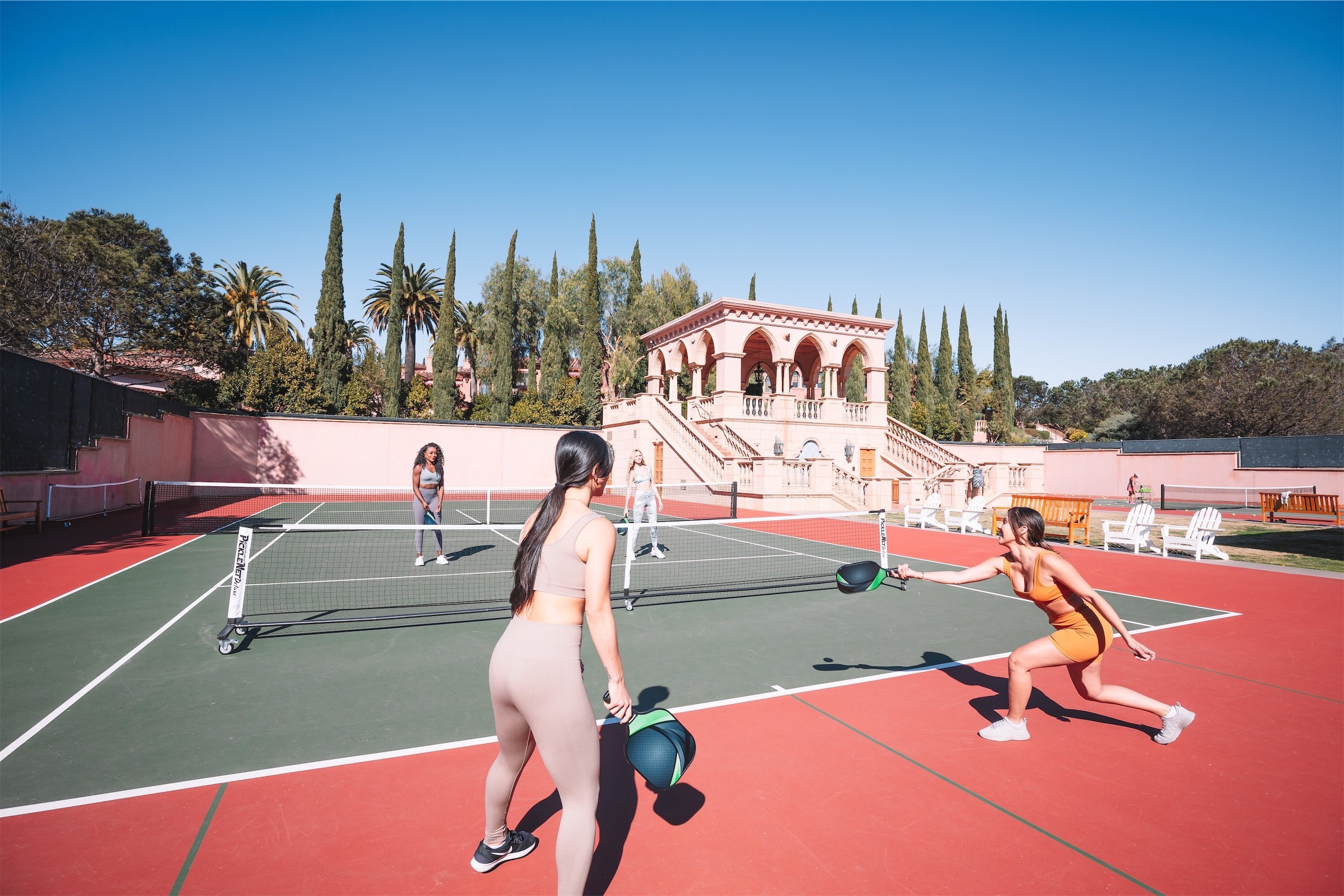 Four women playing pickleball on an outdoor court at Fairmont Grand Del Mar.