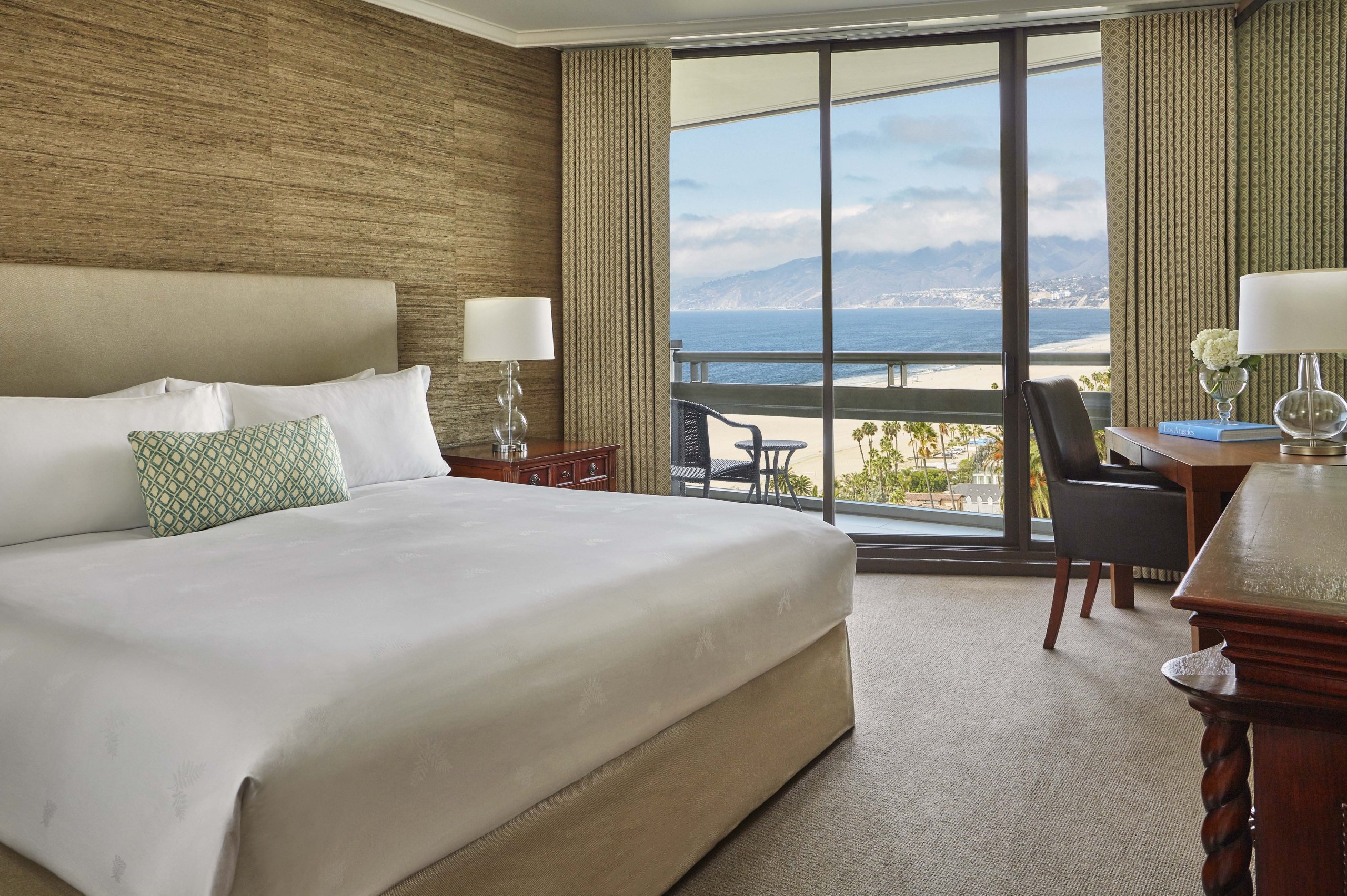 The Premier Ocean View Room at Fairmont Miramar with a balcony overlooking the ocean on a sunny day.