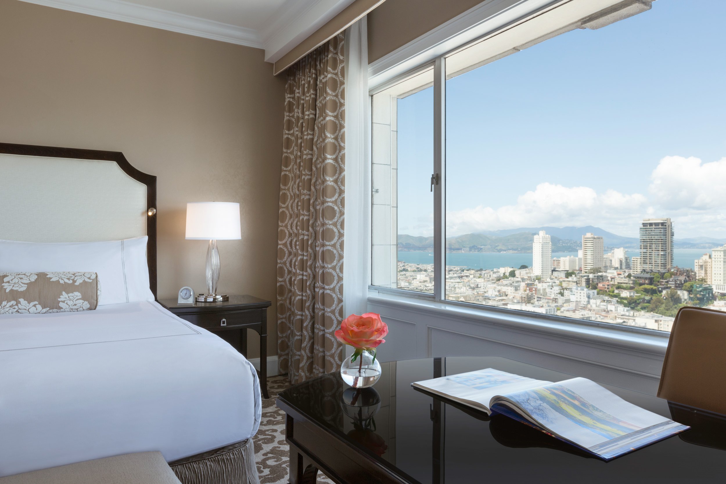 The bed and desk area of the Signature Room at Fairmont San Francisco with sweeping city views.