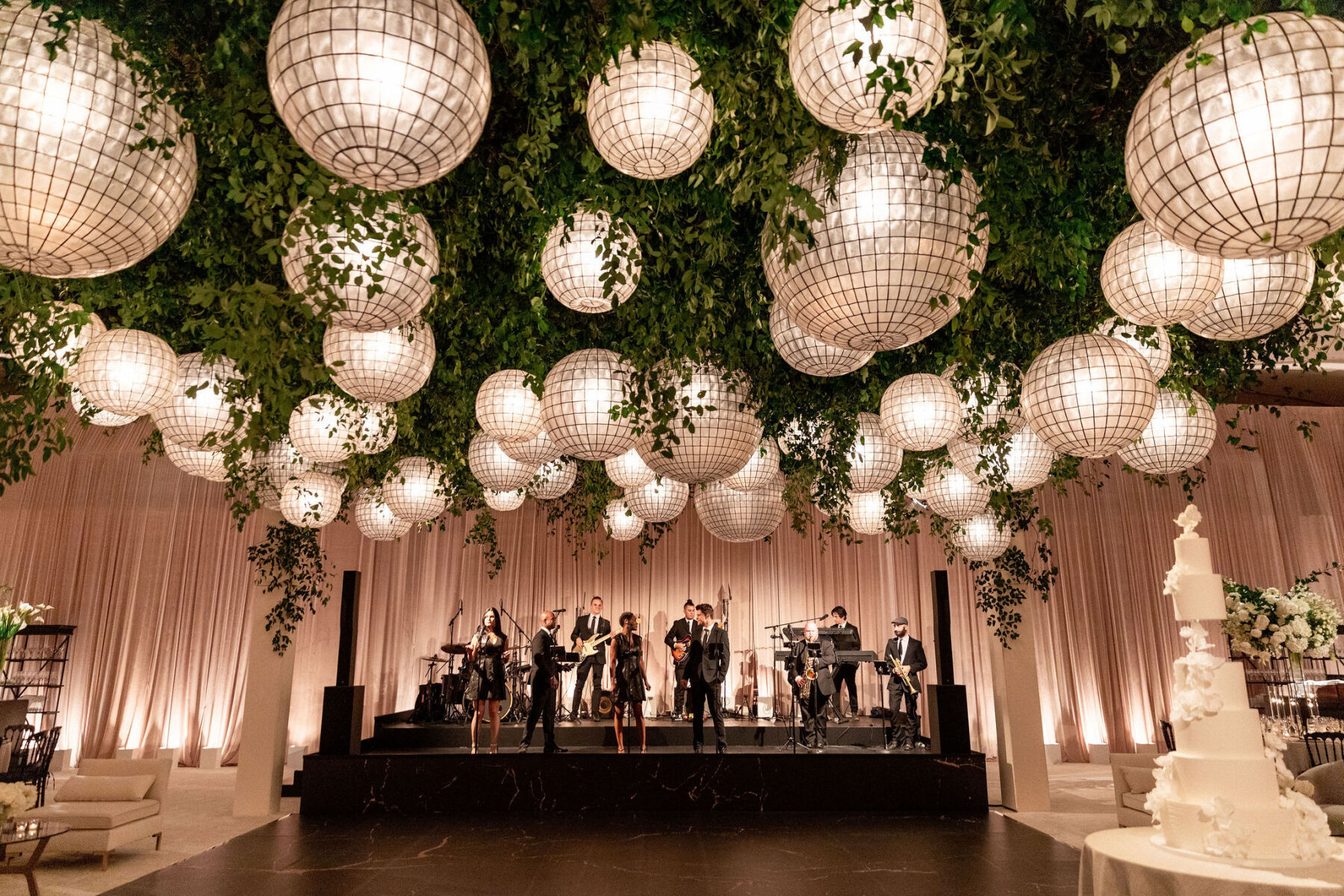 A grand ball room with a jazz band on stage, large globe lights hanging from the ceiling.