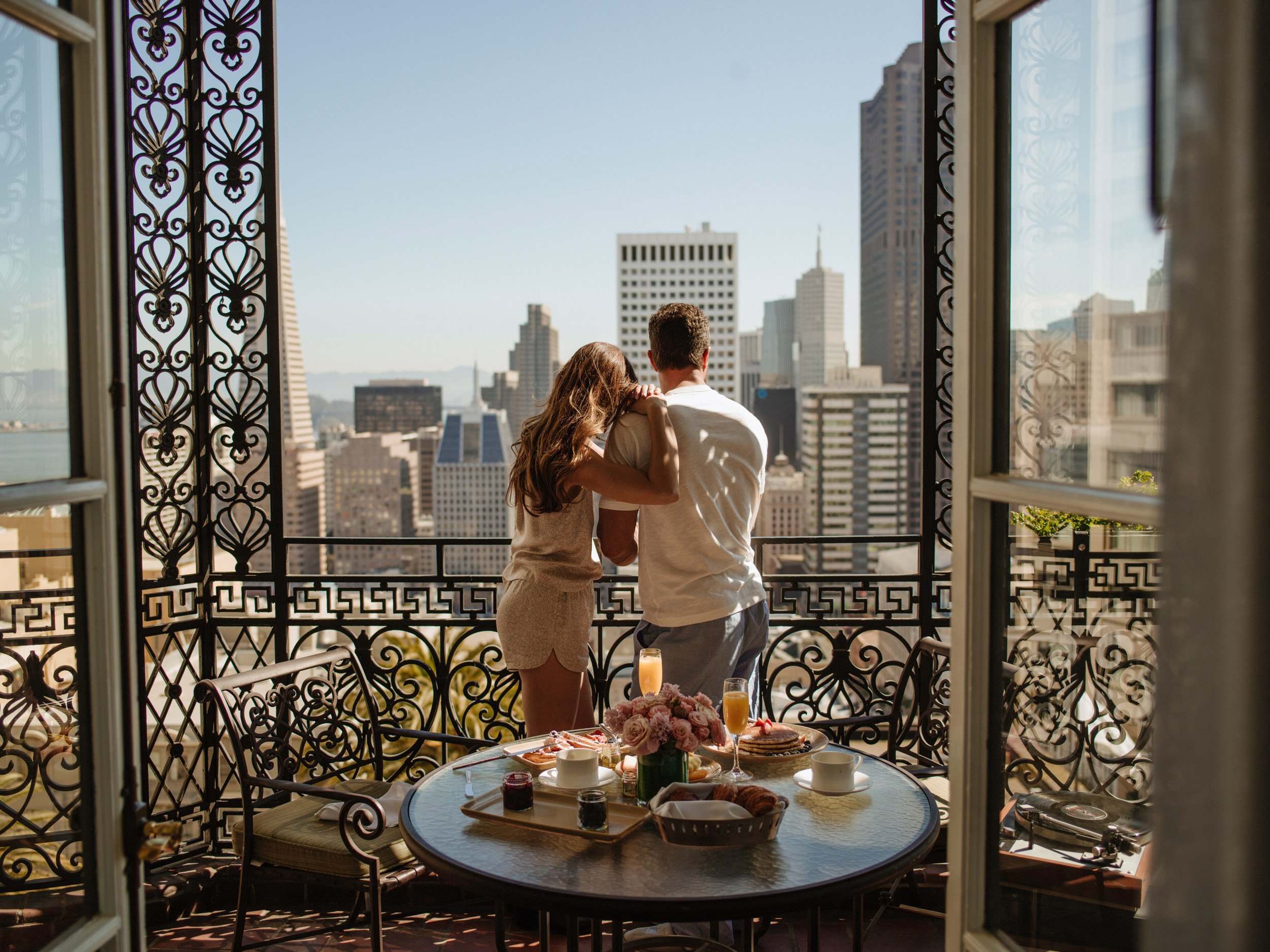 A couple standing on an ornate balcony overlooking San Francisco.