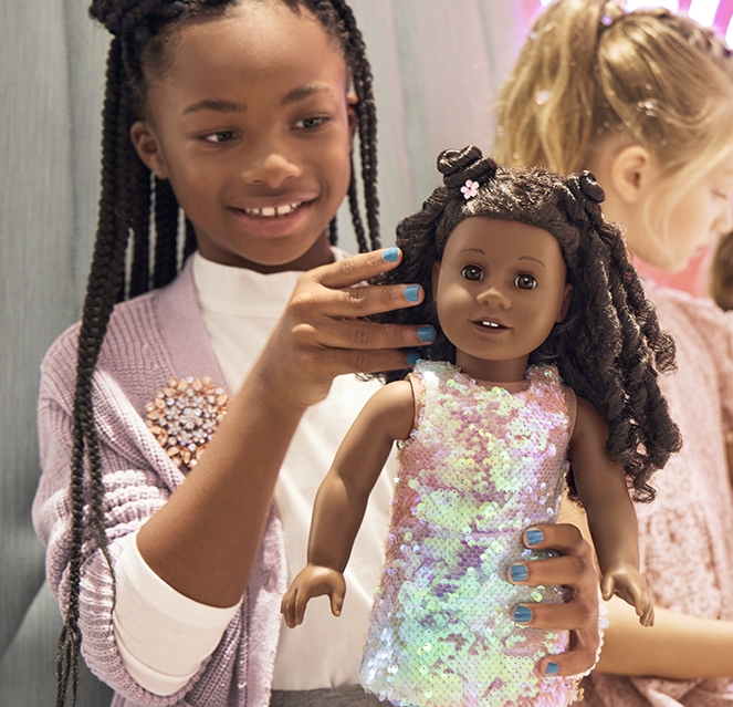 A little girl plays with an American Girl doll.